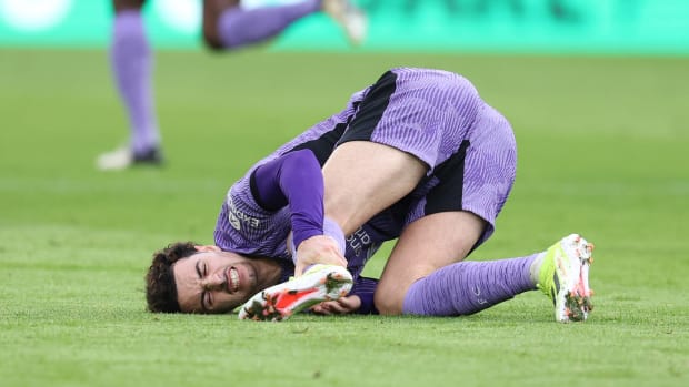 Curtis Jones pictured holding his left ankle after suffering an injury during Liverpool's Premier League away game at Brentford in February 2024